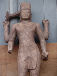 Statue aus Angkor Wat, für die im National Museum kein Platz gefunden wurde, lehnt an der Außenwand.